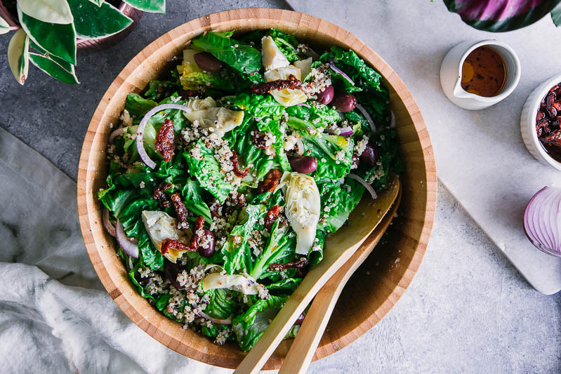 a wooden salad bowl filled with mediterranan greek salad on a blue table