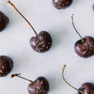 dark chocolate covered cherries with sea salt on white marble background