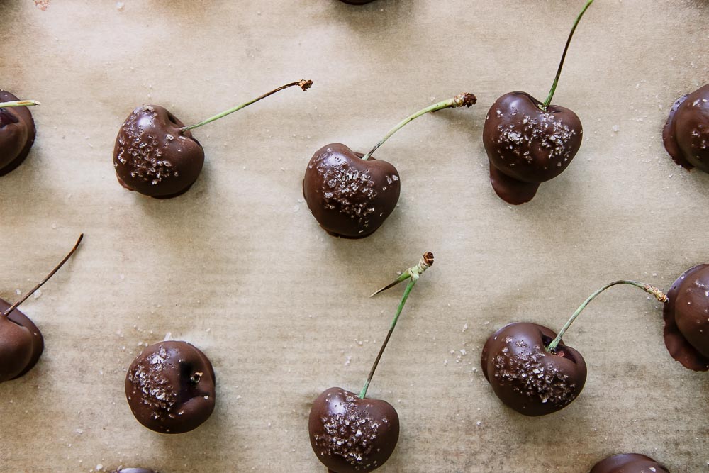 chocolate covered cherries on a sheet of waxed parchment paper on a baking sheet