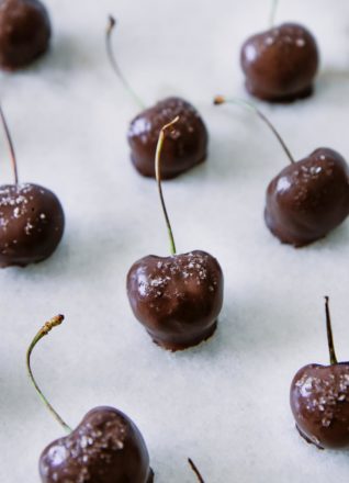 cherries dipped in dark chocolate sauce and sprinkled with sea salt a white table