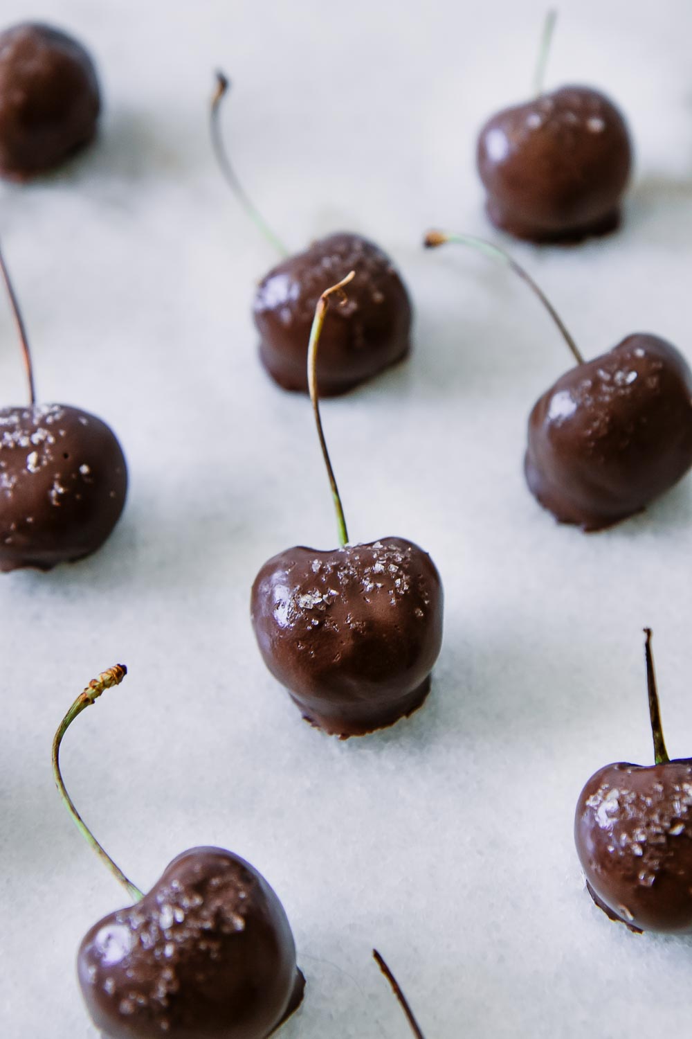 cherries dipped in dark chocolate sauce and sprinkled with sea salt a white table