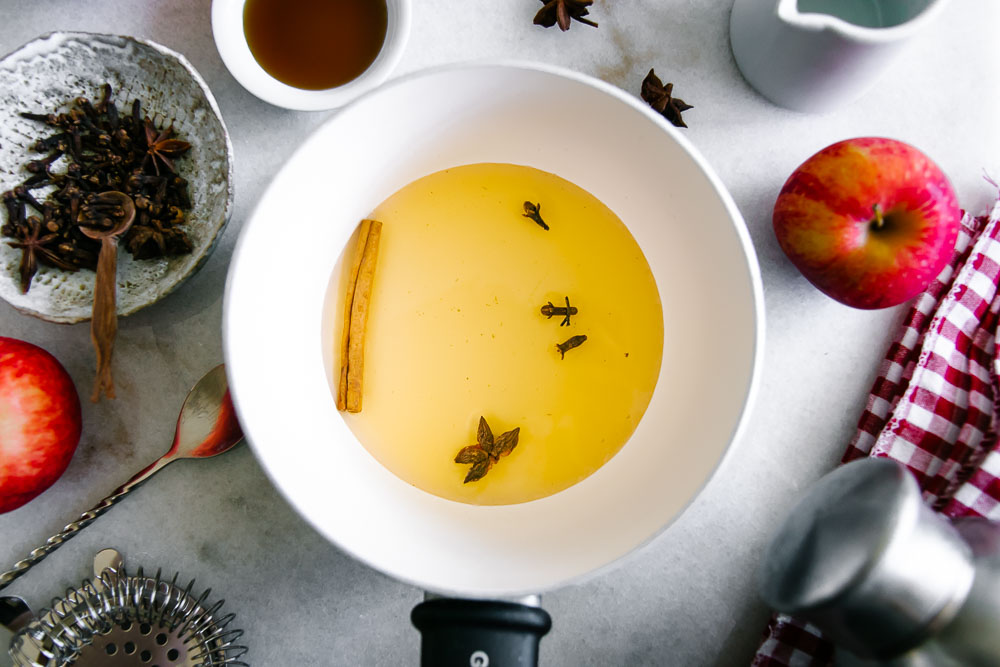 a saucepan with apple cider vinegar and infused spices like cinnamon stick, star anise, and whole cloves