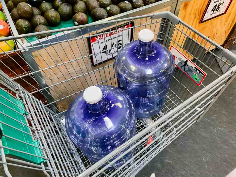 two refillable 5-gallon water bottles in a shopping cart at sprouts