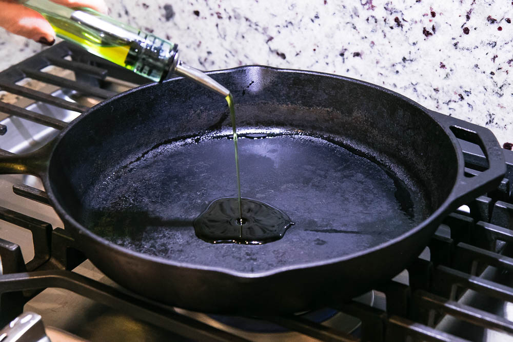 oil drizzling onto a cast iron skillet