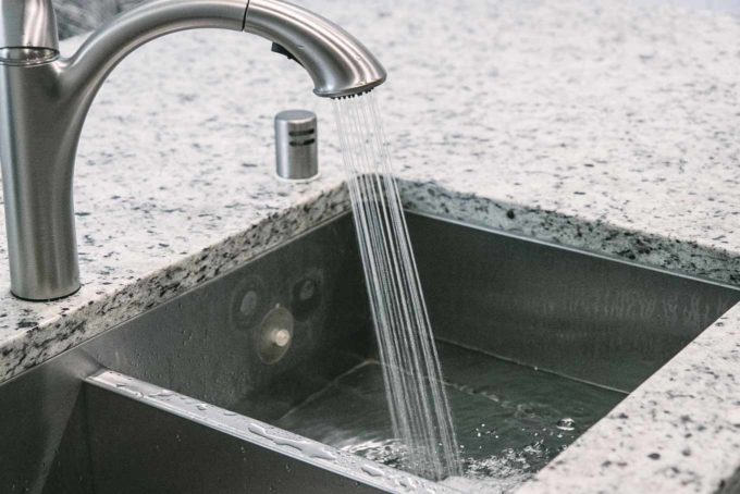 water pouring from a silver faucet into a sink