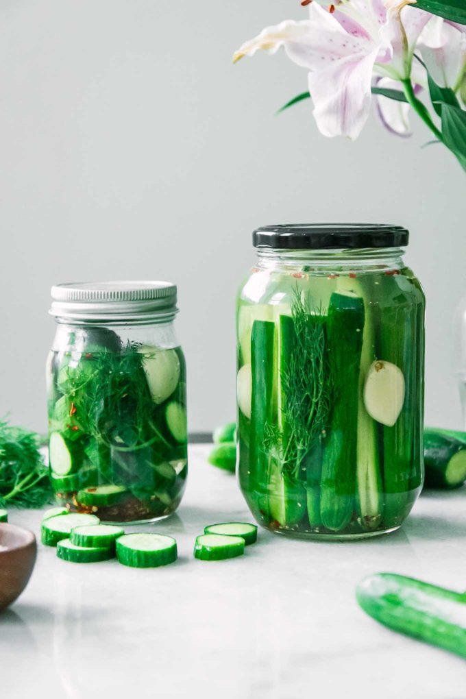 two jars of homemade refrigerator pickles on a white countertop