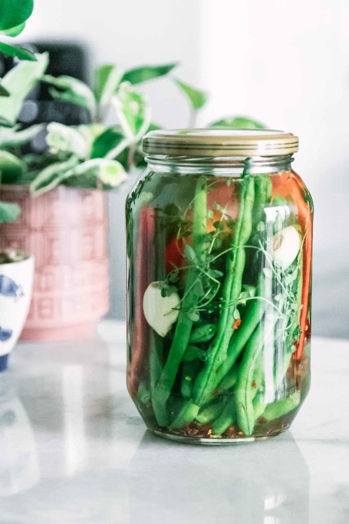 a jar of pickled green beans on a white table