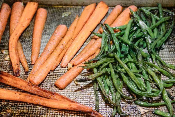 cooked carrots and green beans on a baking sheet