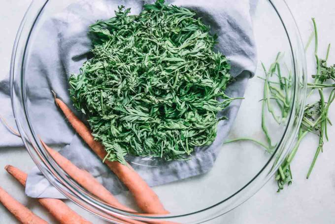 washed and cut carrot leaves and stems in a glass mixing bowl