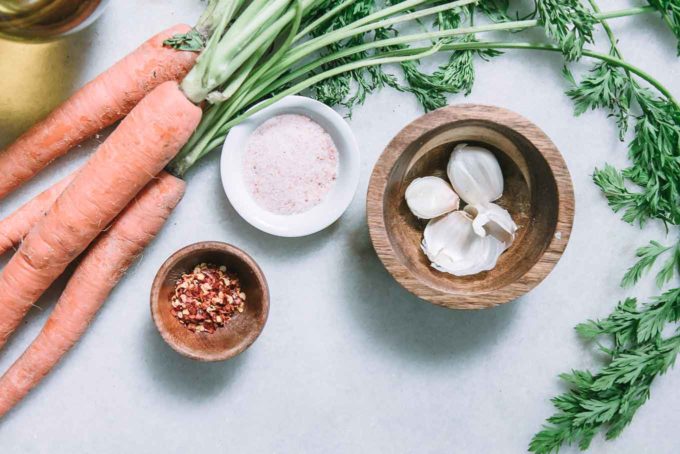 carrots, garlic, salt, pepper, red pepper flakes, and olive oil on a white table