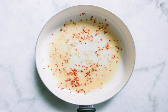 a white pan with olive oil, garlic, and red pepper