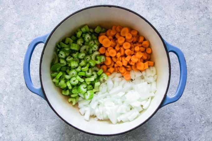 sliced carrots, celery, and onion in a large dutch oven soup pot on a white table