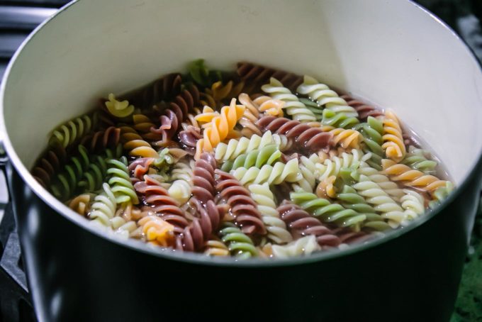 colored rotini pasta boiling in a black pot