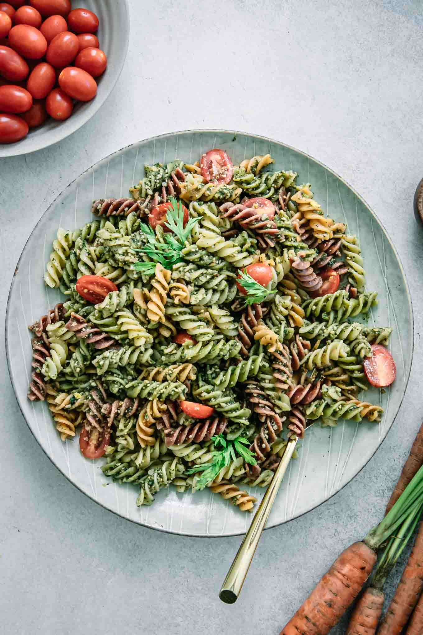 rotini pasta with carrot top pesto sauce on a blue plate with a gold fork