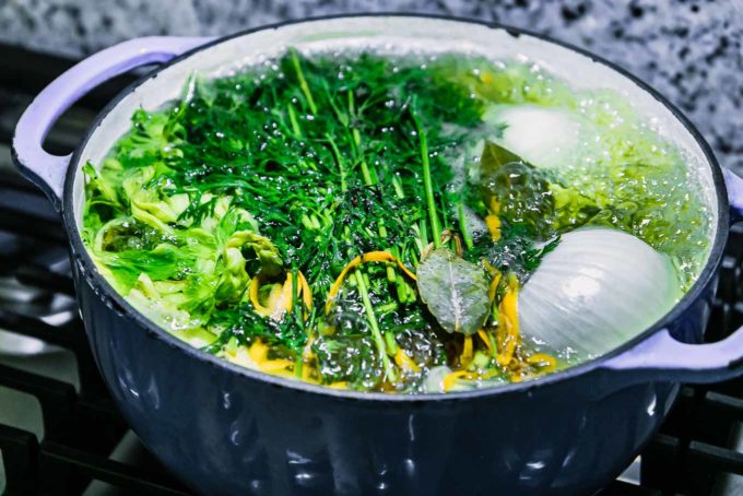 carrot tops in boiling water in a blue soup pot