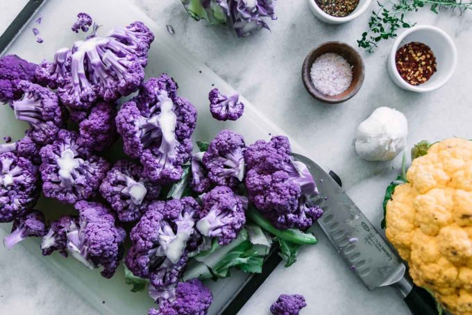 cut purple cauliflower on a cutting board with a knife