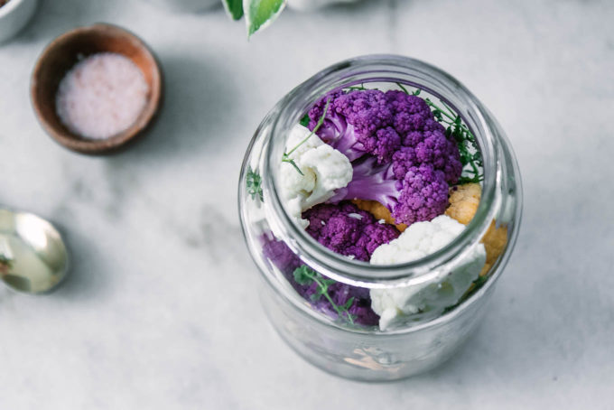 purple cauliflower in a jar with herbs on a white table