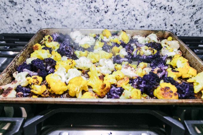roasted cauliflower on a baking sheet on top of a stovetop after baking