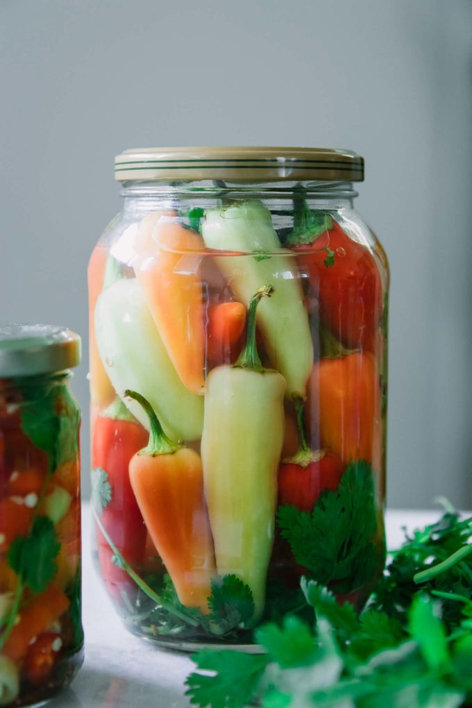 a jar of whole pickled peppers on a white table