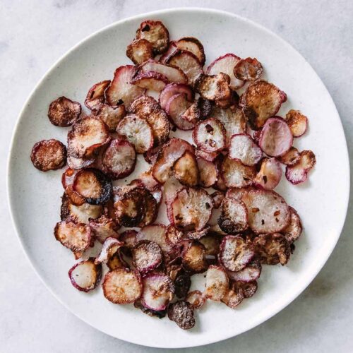 radish chips on a white plate on a marble table
