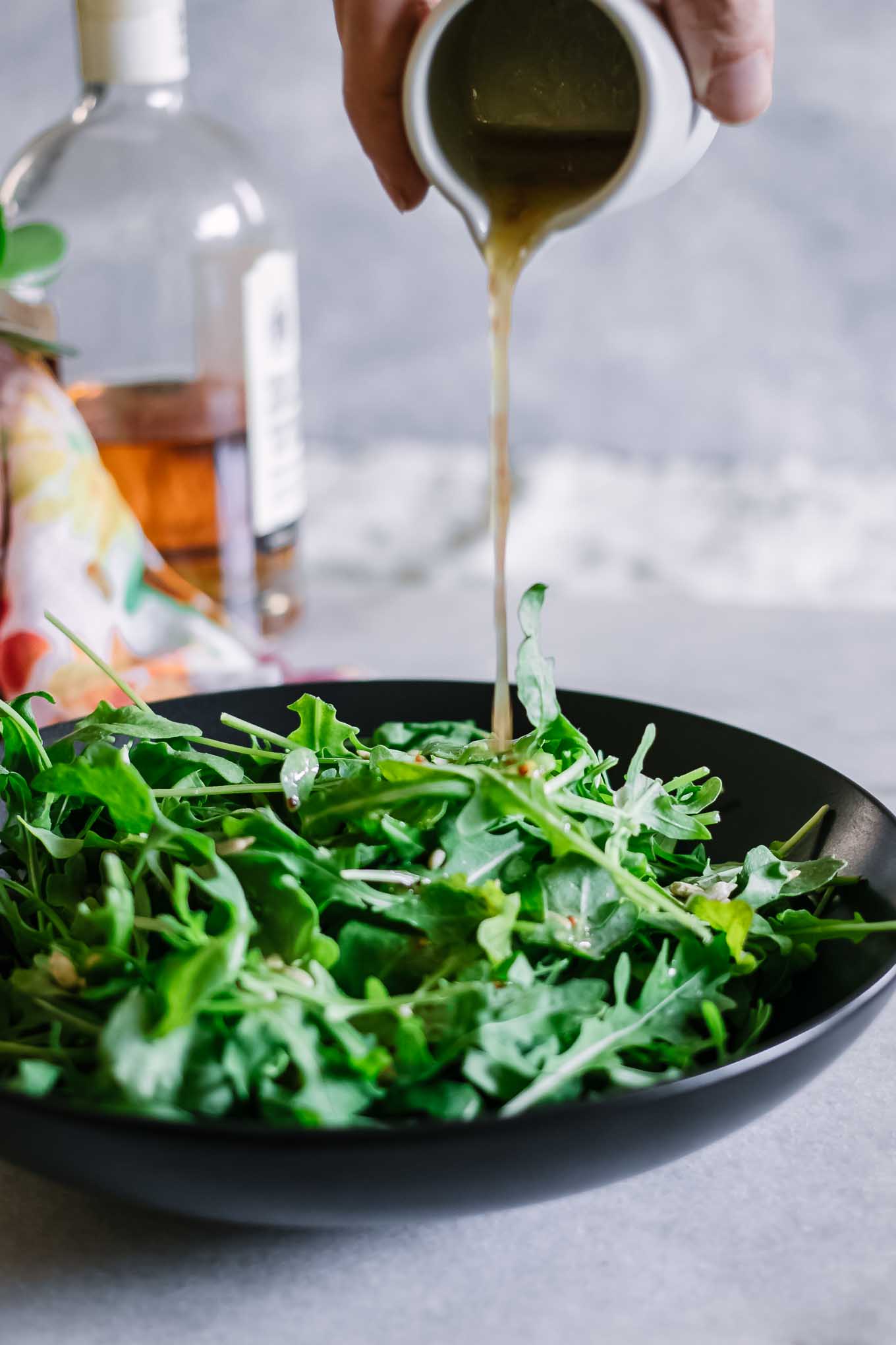 salad dressing pouring onto an arugula salad