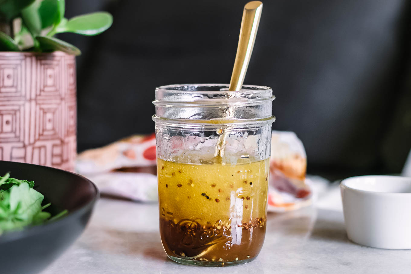 maple vinaigrette in a glass jar with a gold spoon