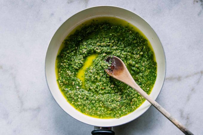 radish greens pesto in a white pan with a wooden spoon