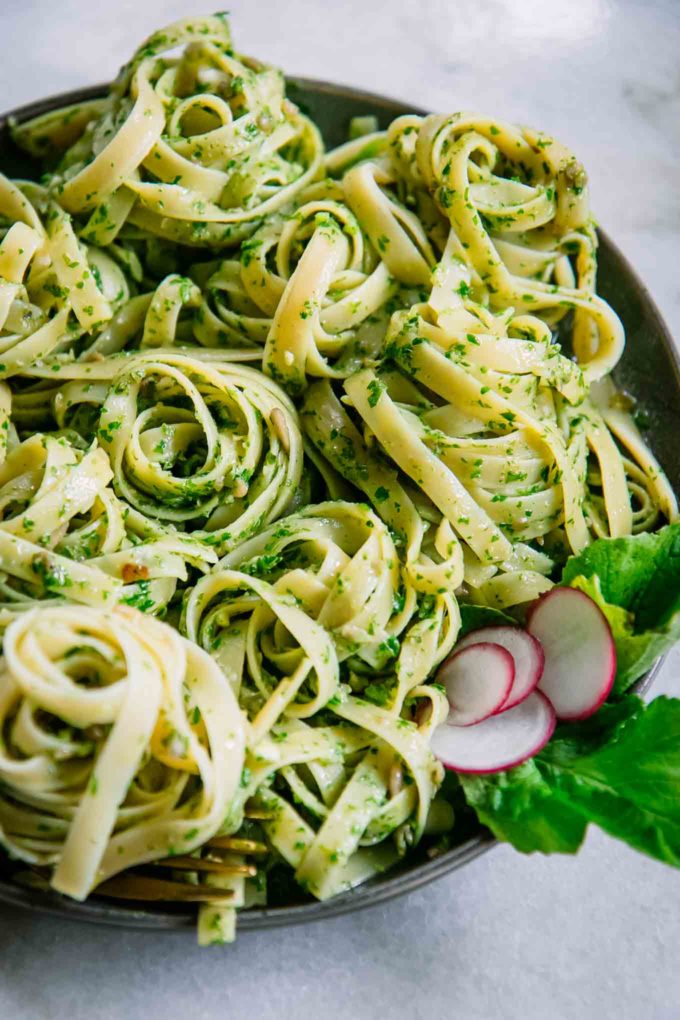 pesto pasta twirled into small rounds on a blue plate