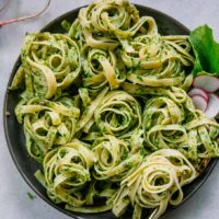 pesto pasta on a blue plate with sliced radishes