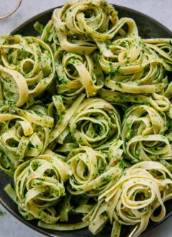 pesto pasta on a blue plate with sliced radishes