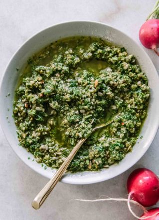 pesto made with radish greens in a white bowl on a white table