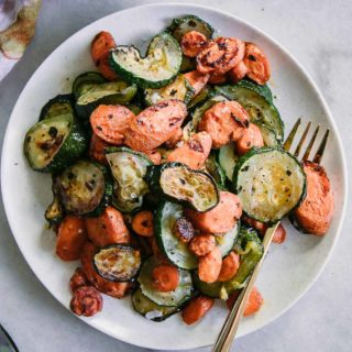 baked carrots and zucchini with garlic on a white plate