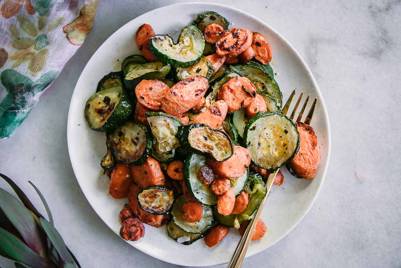 baked carrots and zucchini with garlic on a white plate