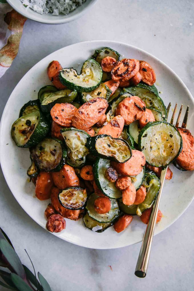 roasted sliced carrots and zucchini on a white plate with a gold fork