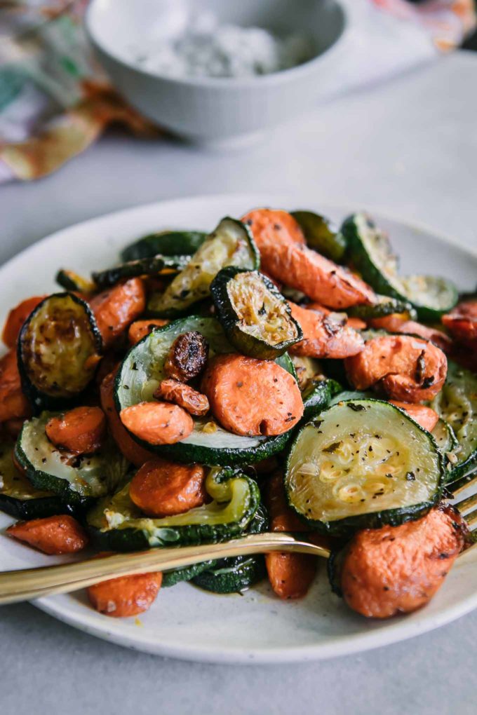 close up photo of roasted carrots and zucchini on a white plate