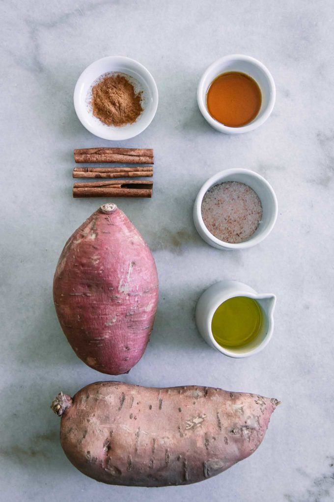 sweet potatoes, olive oil, salt, maple syrup, and cinnamon on a white table