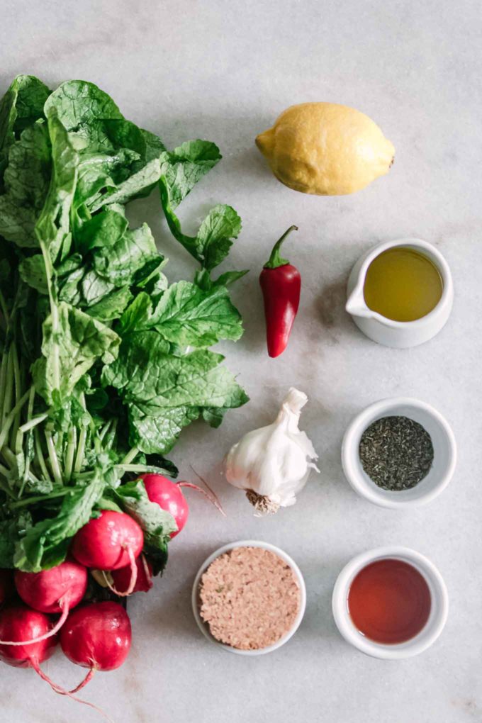 a bunch of radishes and bowls of radishes, red wine vinegar, oregano, salt, lemon, red pepper, and garlic