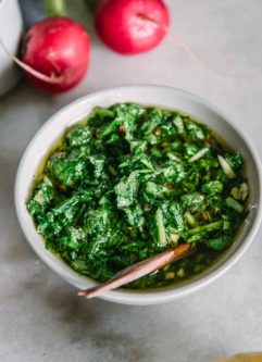 chimichurri made from radish greens in a white bowl on a marble table