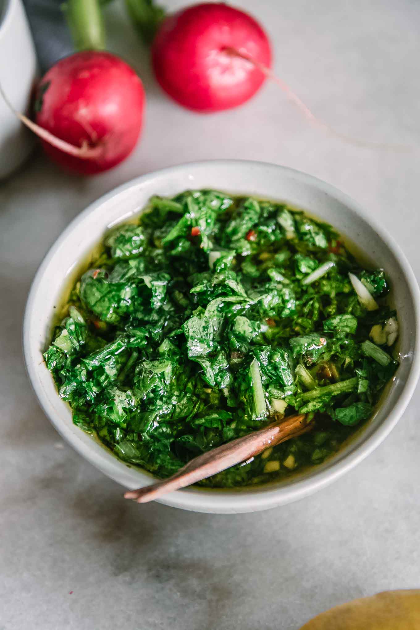 chimichurri made from radish greens in a white bowl on a marble table