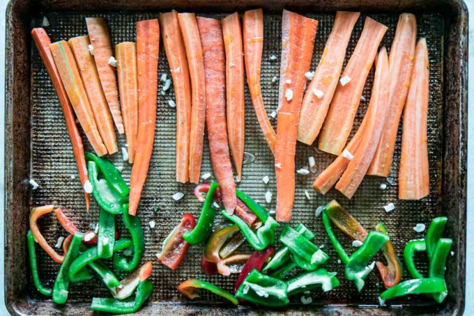 sliced carrots and bell peppers on a sheet pan