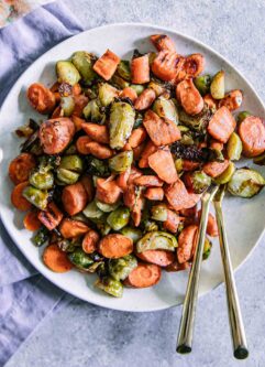 roasted brussels sprouts and carrots on a white plate with a gold fork