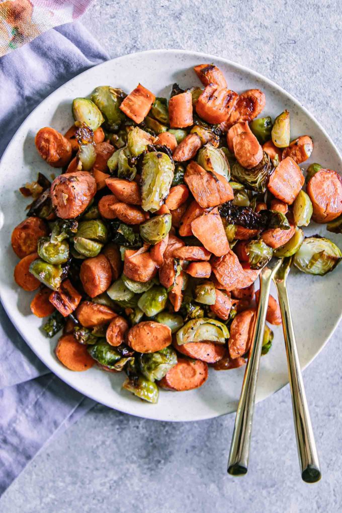 roasted brussels sprouts and carrots on a white plate with a gold fork