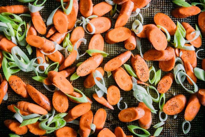 sliced carrots and leeks on a baking sheet