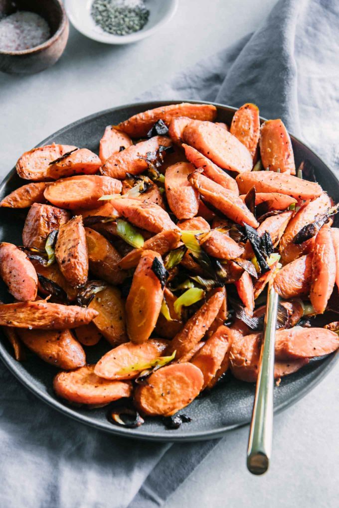 a carrot and leek side dish on a white table with a blue napkin