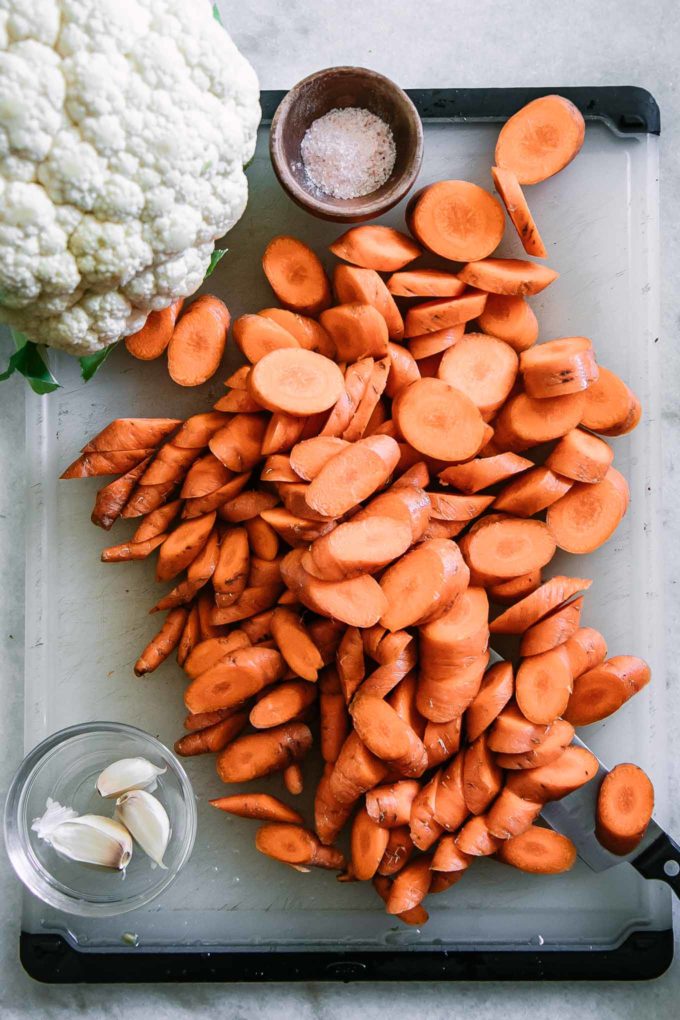 sliced carrots and cauliflower on a white cutting board