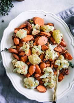 roasted cauliflower and carrots on a white plate with a gold fork on a white table