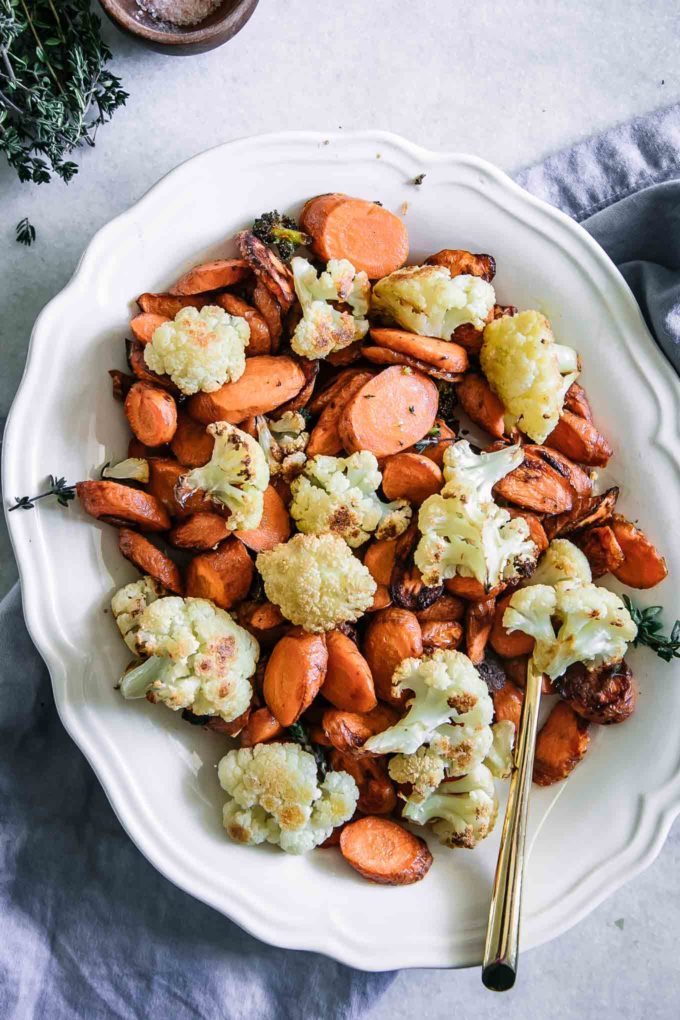 roasted cauliflower and carrots on a white plate with a gold fork on a white table