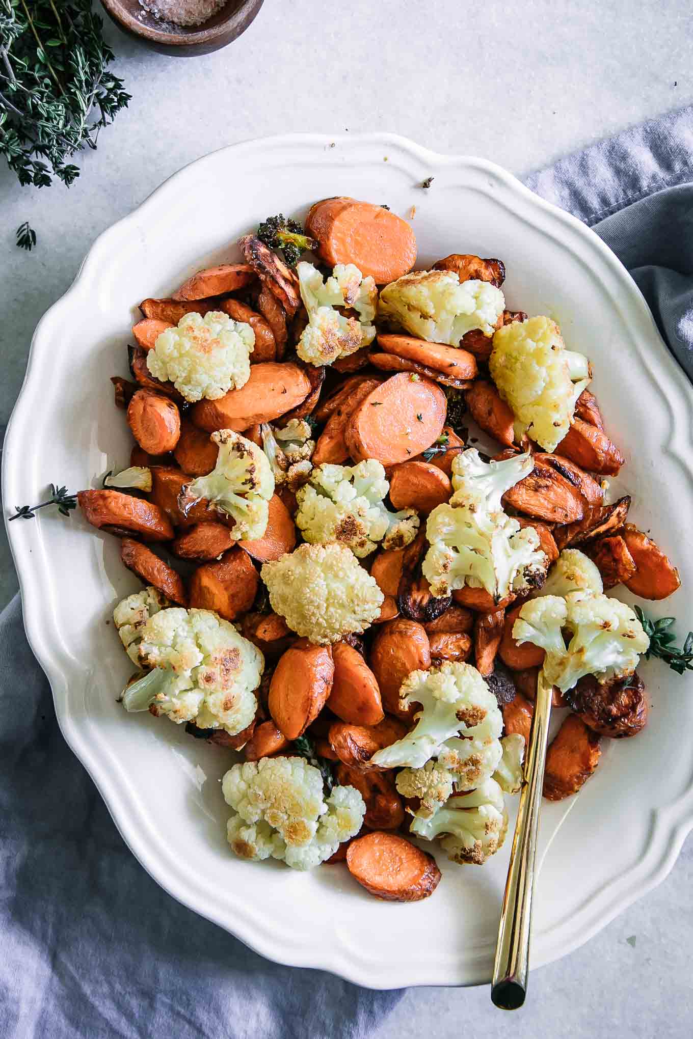 roasted cauliflower and carrots on a white plate with a gold fork on a white table