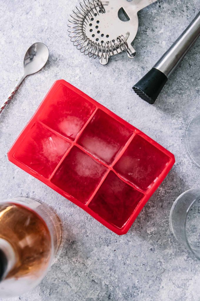 a silicon ice tray, muddler, and other cocktail tools on a blue table