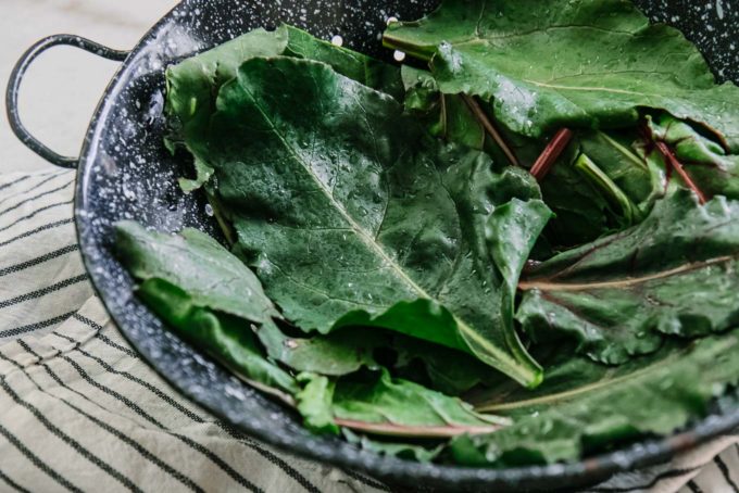 beet leaves drying in a colander on a white table